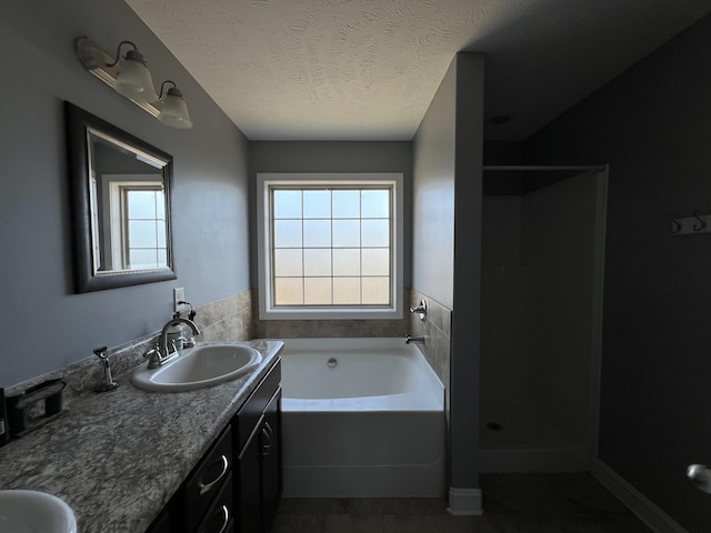 bathroom with a textured ceiling, separate shower and tub, and vanity