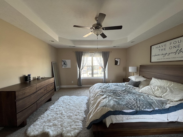 bedroom featuring ceiling fan, a tray ceiling, and light colored carpet