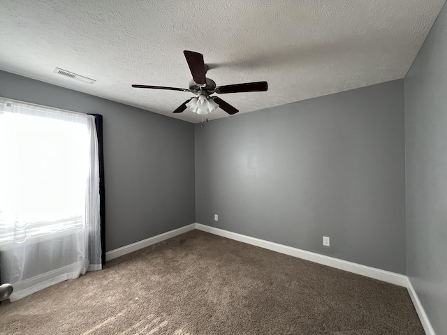 carpeted spare room featuring a textured ceiling and ceiling fan