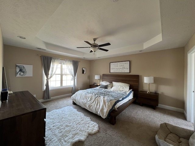 bedroom with a raised ceiling, ceiling fan, a textured ceiling, and carpet flooring