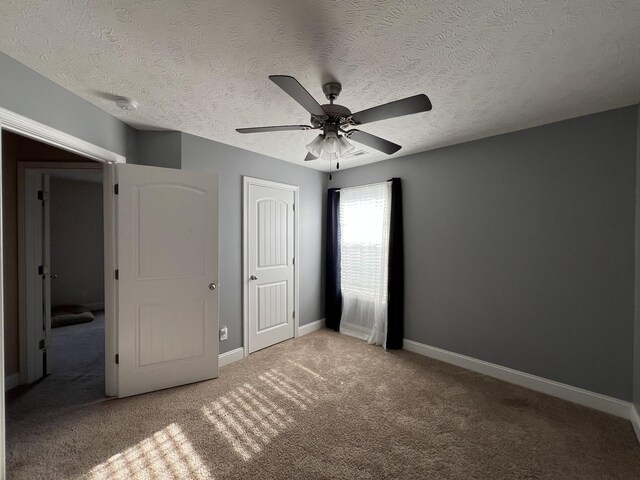 unfurnished bedroom featuring a textured ceiling, ceiling fan, and carpet flooring