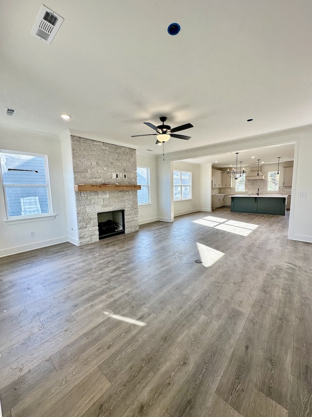 unfurnished living room with hardwood / wood-style flooring, a fireplace, and ceiling fan with notable chandelier