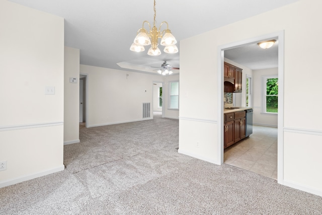 interior space with light carpet, dishwasher, ceiling fan with notable chandelier, and hanging light fixtures