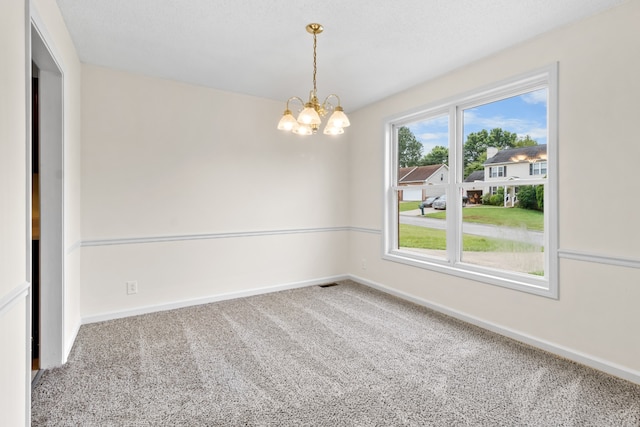 carpeted spare room featuring a chandelier