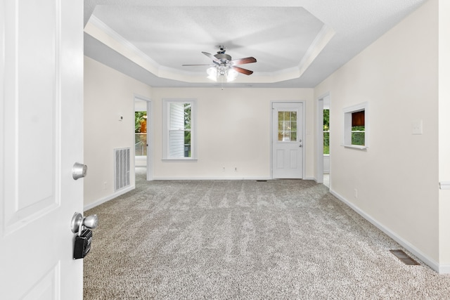 spare room with light carpet, crown molding, a tray ceiling, and ceiling fan