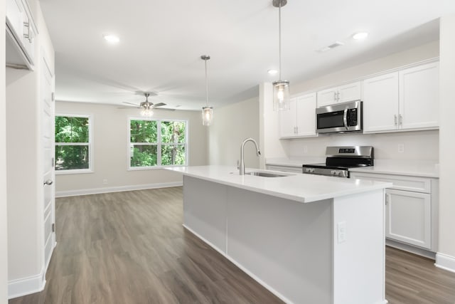 kitchen featuring appliances with stainless steel finishes, decorative light fixtures, white cabinetry, and an island with sink