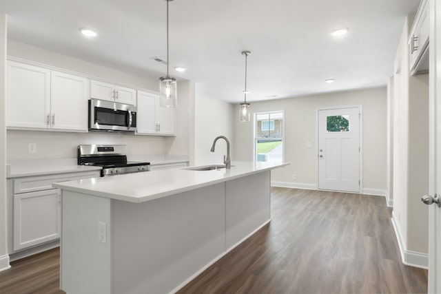 kitchen with a center island with sink, white cabinets, decorative light fixtures, and stainless steel appliances