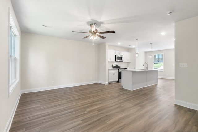 unfurnished living room featuring dark wood-type flooring and ceiling fan