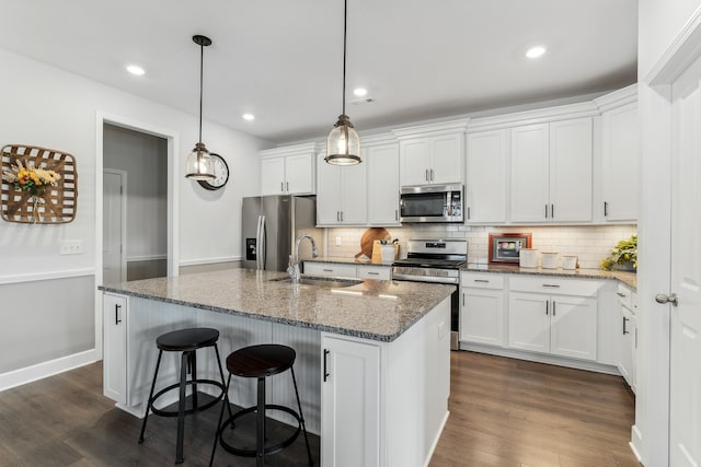 kitchen featuring appliances with stainless steel finishes, white cabinetry, sink, and a center island with sink