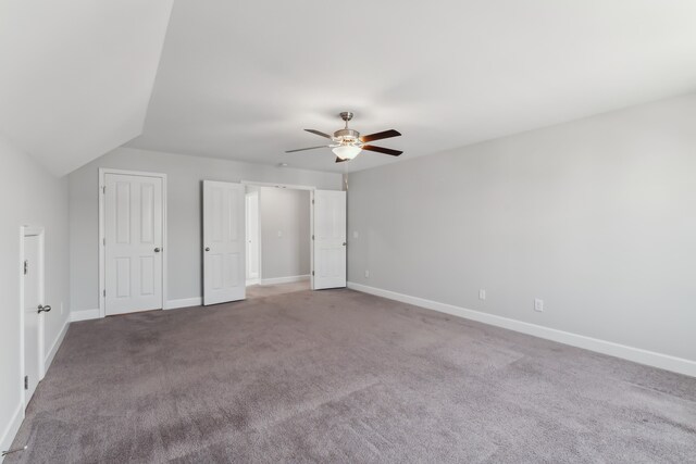 unfurnished bedroom featuring carpet flooring, vaulted ceiling, and ceiling fan