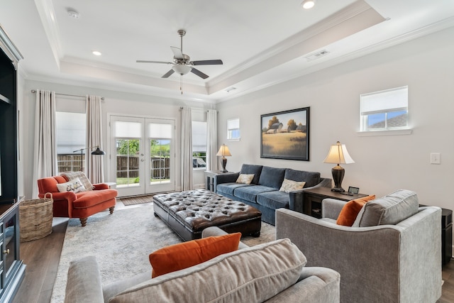 living room featuring crown molding, a tray ceiling, french doors, and dark hardwood / wood-style flooring