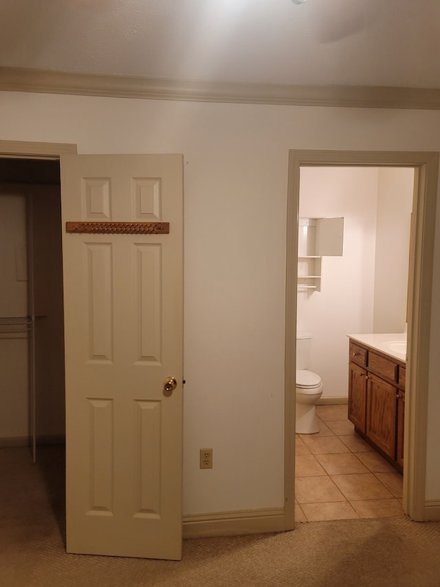 bathroom with tile patterned floors, crown molding, vanity, and toilet