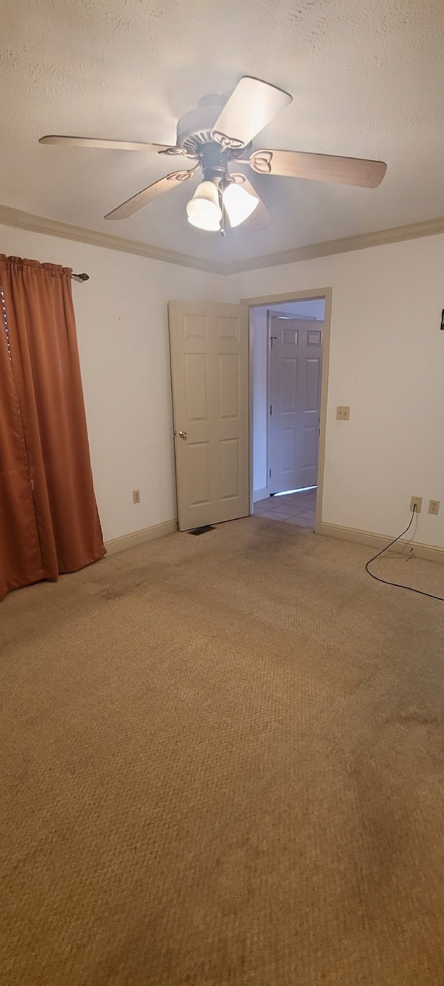 unfurnished room featuring baseboards, ceiling fan, ornamental molding, light carpet, and a textured ceiling