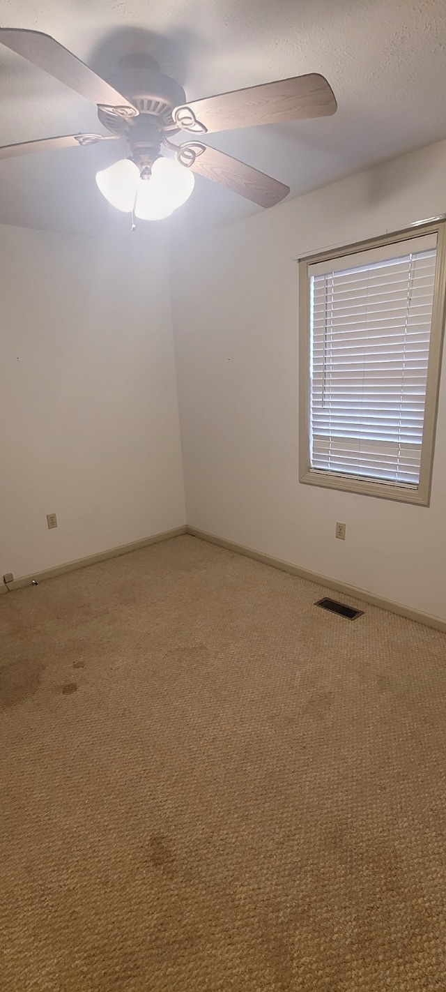 carpeted spare room featuring ceiling fan