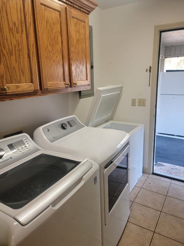 laundry room featuring cabinet space, washing machine and dryer, and light tile patterned flooring