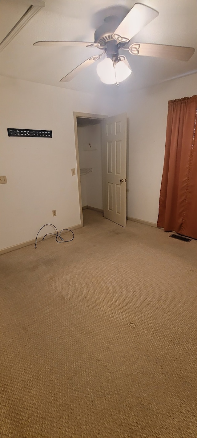 empty room with visible vents, light colored carpet, and a ceiling fan