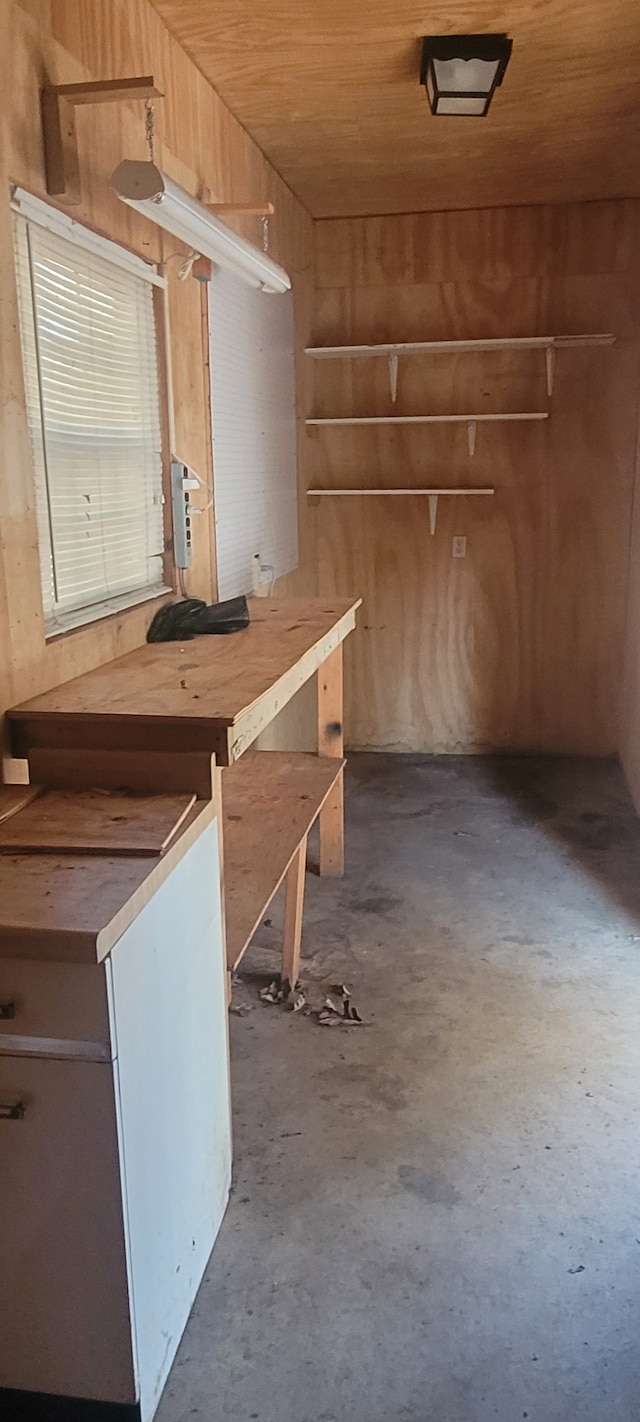 interior space with wood walls, concrete flooring, and wooden ceiling