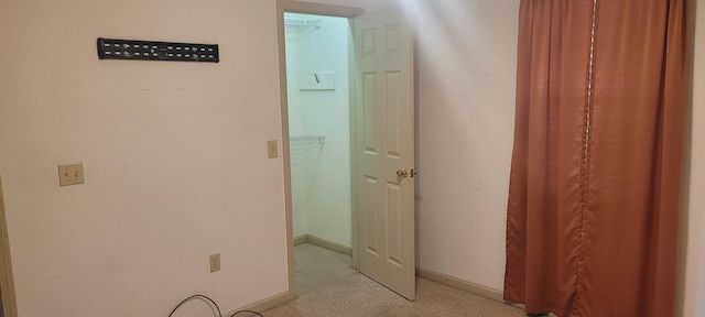 corridor featuring baseboards and light carpet