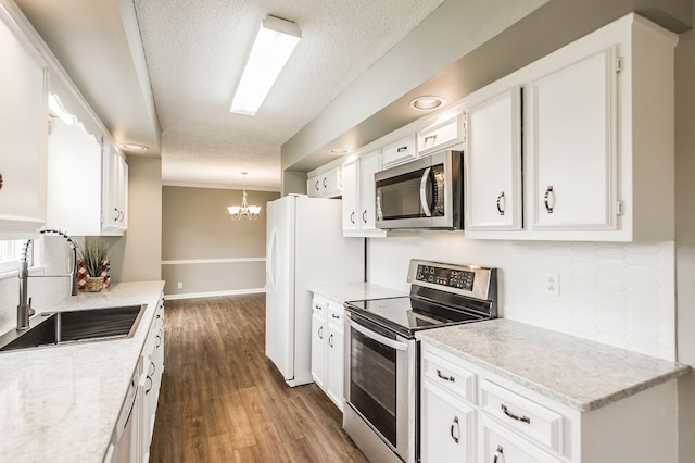 kitchen with sink, dark wood-type flooring, stainless steel appliances, white cabinets, and decorative light fixtures