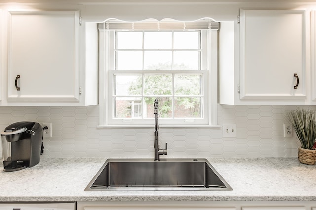 kitchen featuring white cabinetry, sink, and light stone counters