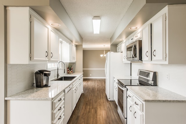 kitchen with appliances with stainless steel finishes, white cabinetry, sink, light stone counters, and dark wood-type flooring