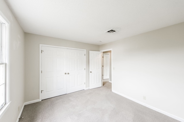 unfurnished bedroom featuring a closet and light carpet