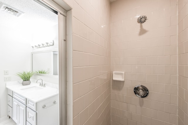 bathroom featuring a tile shower and vanity