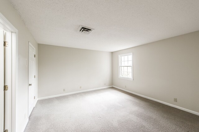 unfurnished room with light colored carpet and a textured ceiling