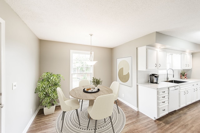 dining area featuring sink, hardwood / wood-style floors, and a textured ceiling