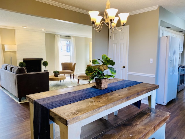 dining space with crown molding, a large fireplace, dark hardwood / wood-style flooring, and an inviting chandelier