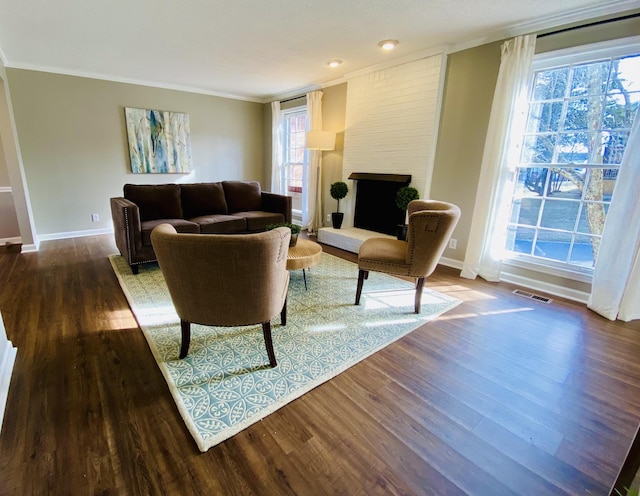 living room with a brick fireplace, crown molding, and dark hardwood / wood-style floors