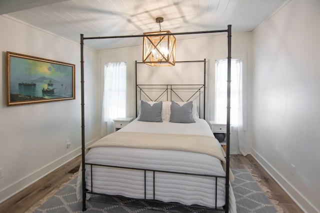 bedroom featuring a notable chandelier, ornamental molding, and dark wood-type flooring