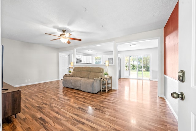 living room with a textured ceiling, wood-type flooring, and ceiling fan