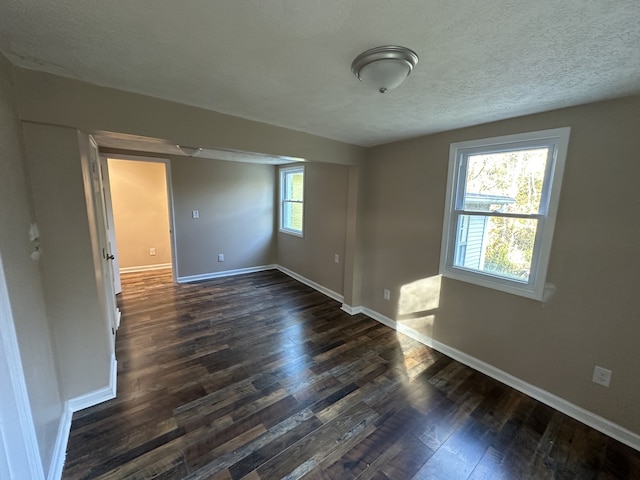 unfurnished room with dark wood-type flooring, a textured ceiling, and a healthy amount of sunlight