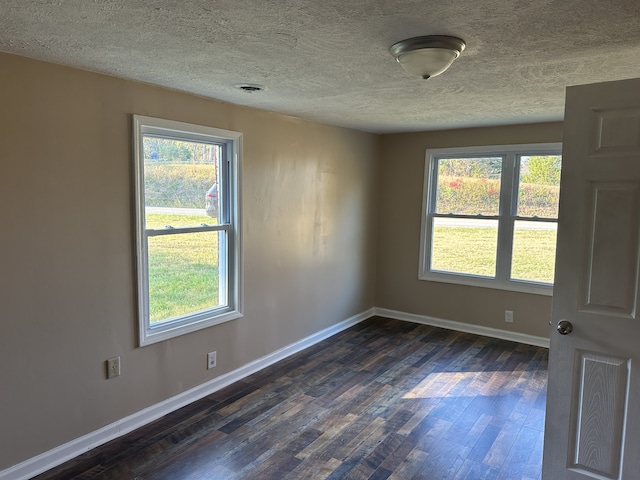 spare room with dark hardwood / wood-style floors and a textured ceiling