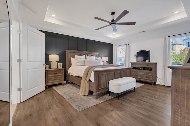 bedroom featuring ceiling fan, a raised ceiling, and multiple windows