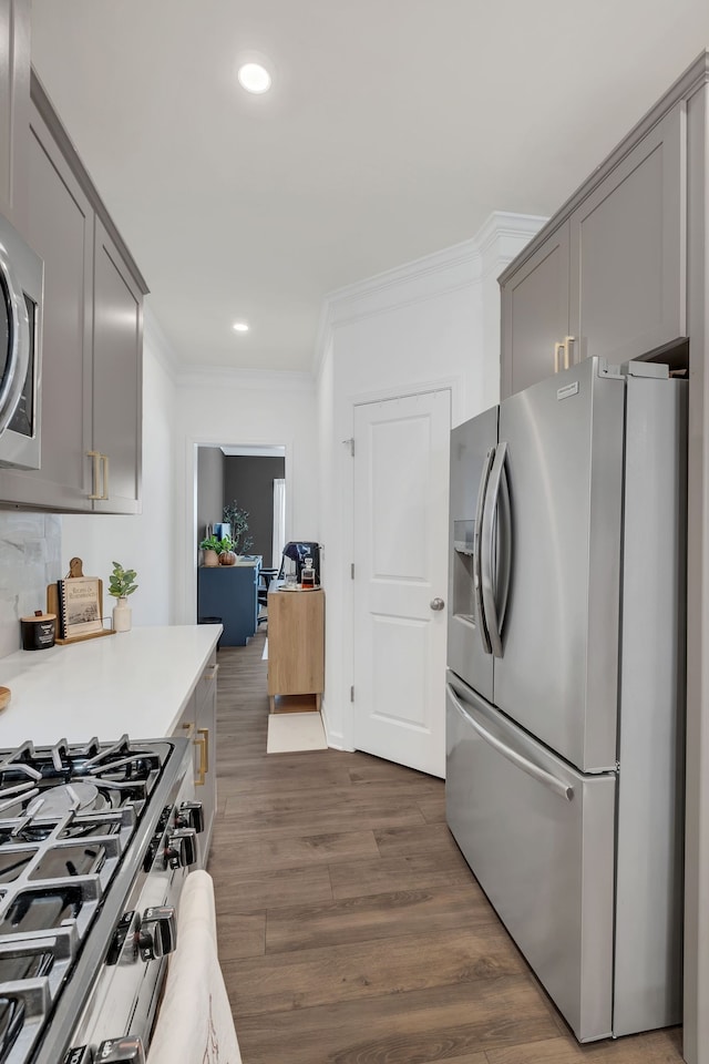 kitchen featuring gray cabinetry, backsplash, stainless steel appliances, crown molding, and dark hardwood / wood-style floors