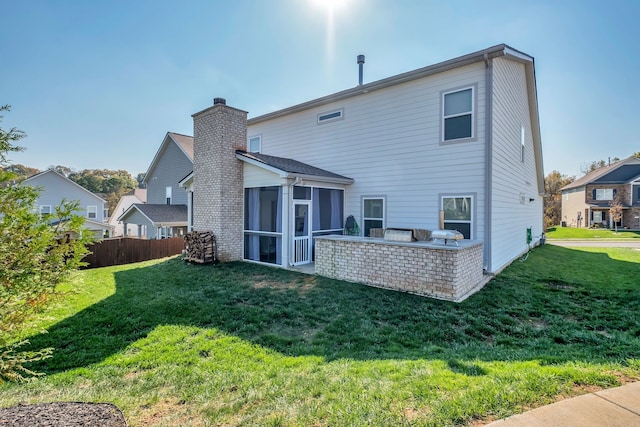 rear view of house featuring a yard, a patio area, and a sunroom