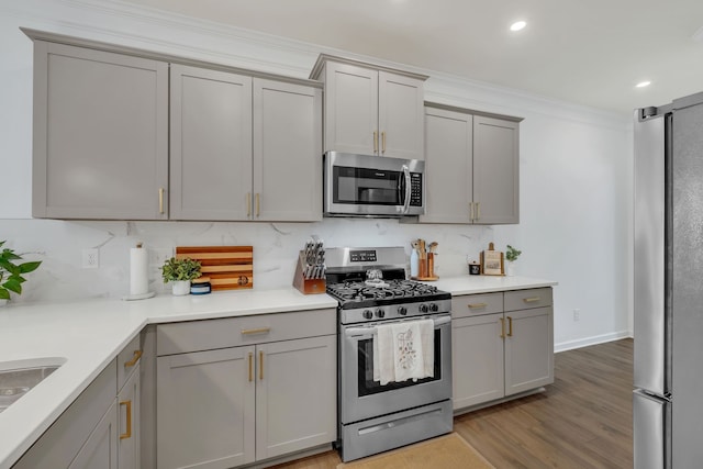 kitchen with backsplash, stainless steel appliances, light wood-type flooring, and gray cabinets