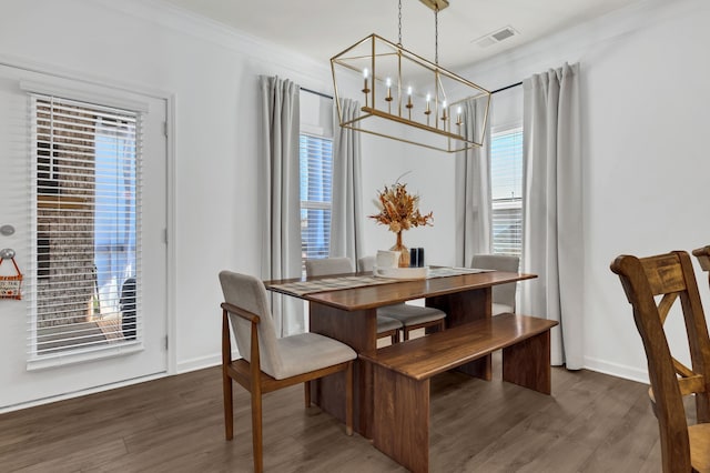 dining area featuring crown molding, dark hardwood / wood-style floors, a healthy amount of sunlight, and a notable chandelier