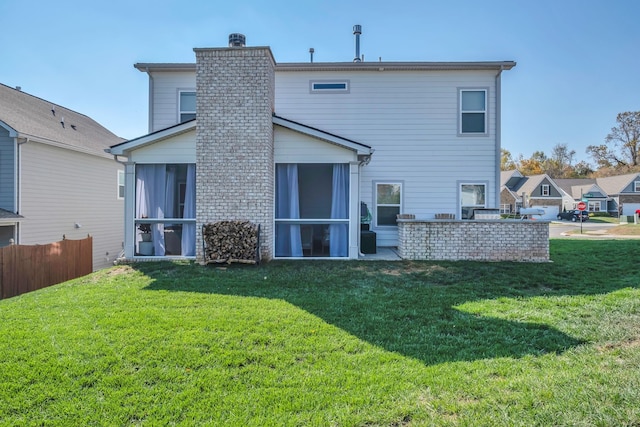 rear view of house featuring a patio, a lawn, and a sunroom