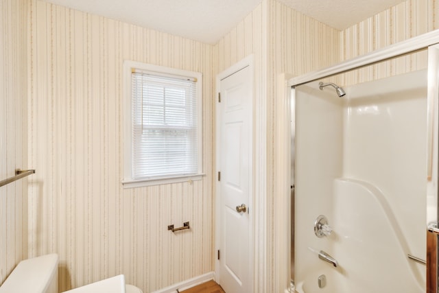 bathroom with tub / shower combination, toilet, and a textured ceiling