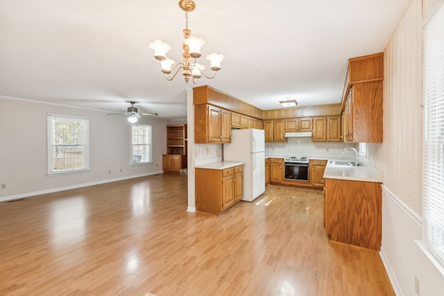 kitchen with hanging light fixtures, white fridge, light hardwood / wood-style flooring, and sink