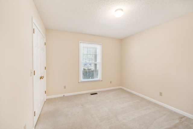 carpeted empty room featuring a textured ceiling