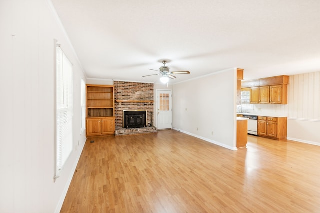 unfurnished living room with ornamental molding, sink, light hardwood / wood-style floors, a brick fireplace, and ceiling fan