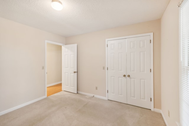 unfurnished bedroom with a textured ceiling, light carpet, and a closet