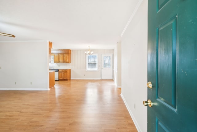 interior space with ornamental molding, light wood-type flooring, and an inviting chandelier