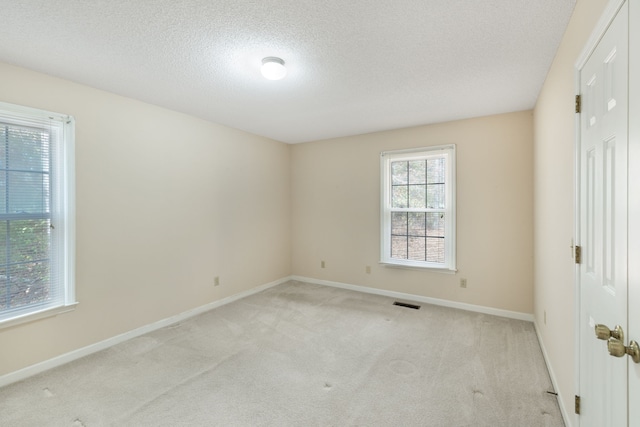 unfurnished room featuring a textured ceiling and light carpet