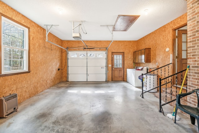 garage with a garage door opener, heating unit, and washer and clothes dryer