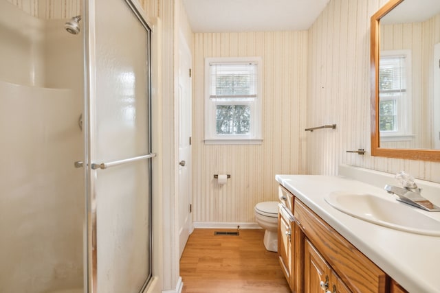 bathroom with toilet, an enclosed shower, vanity, and hardwood / wood-style floors